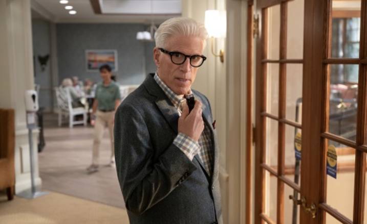 Ted Danson in a office hallway looking into camera and talking into a miniture microphone.