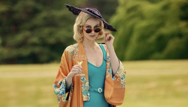 Outrageous Mitford Sisters Cast Member in a garden wearing summer clothes, a hat and wearing sunglasses