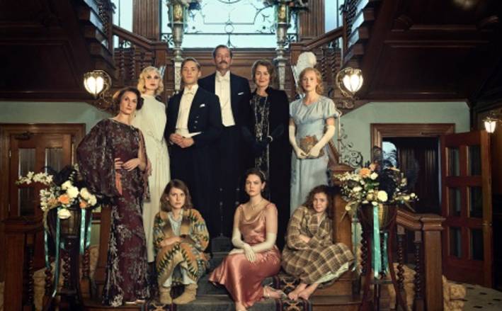 Cast members of Outrageous standing and sitting on a staircase wearing 1920's period clothing